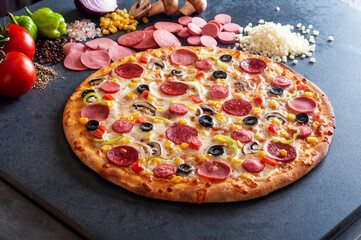 Pepperoni and sausage pizza on black stone background.