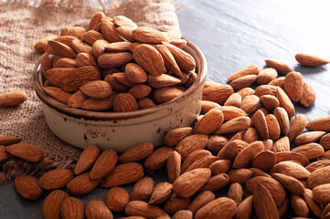 Roasted almonds on stone table and in clay bowl