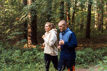 people running in forest, young man and woman jogging in park