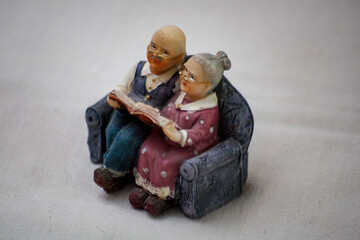 Sculpture of grandparents on the couch reading a book