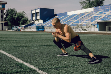 Young sportsman doing exercise squats at stadium