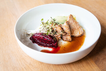 Delicious roasted pork filet cooked with smashed potatoes and smashed beetroots served in white plate.