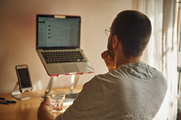 Contemplative man looking directly at his laptop