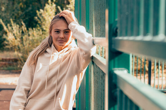 young woman in hoodie posing at sports ground