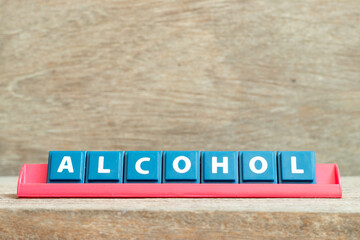 Tile alphabet letter with word alcohol in red color rack on wood background