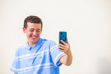 chico joven sonriente hablando en una videoconferencia con telefono movil aislado fondo amarillo
