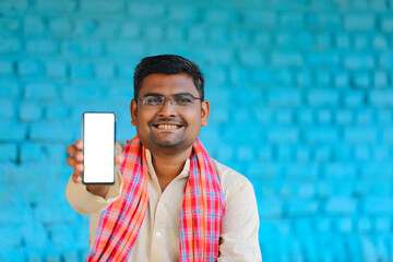 technology concept : Young indian farmer showing smartphone at his home