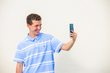 chico joven sonriente hablando en una videoconferencia con telefono movil aislado fondo amarillo