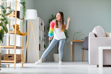 Full length body size view of attractive cheerful crazy overjoyed girl dancing with fluffy brush having fun vacation at home indoors