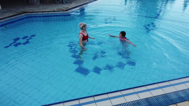 Beautiful woman with her daughter in swimming pool