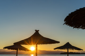 Sunrise and beach umbrellas. Golden sunrise, parasol  view, Ionian Sea, Greece