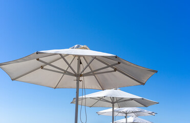 Fototapeta na wymiar White parasols. Many white beach umbrellas under the blue sky.