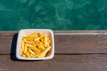Chips on the beach.  Top photo of a white polystyrene carton filled with chips. 