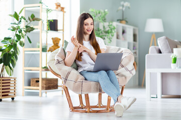 Portrait of attractive cheerful girl sitting in chair using laptop discussing conference at home light living room indoors