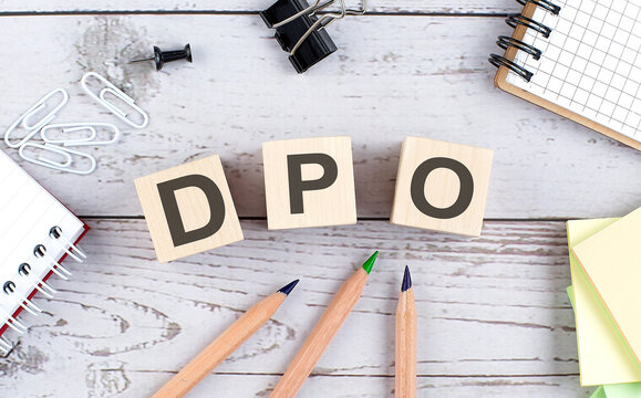 DPO text on wooden block with office tools on wooden background