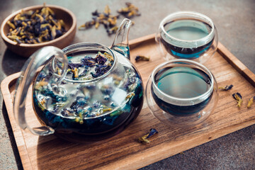 Obraz na płótnie Canvas Thai Butterfly pea tea in a glass teapot and cups on a table.