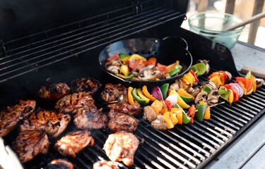 Vegetable skewers and chicken on the grill of a gas bbq.