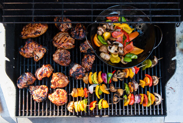 Overhead of vegetable skewers and chicken on the grill of a gas bbq.