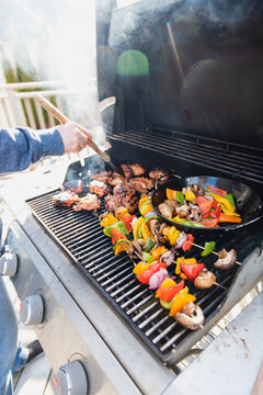 Hand Grilling Chicken And Vegetables Outdoors On A Gas Bbq Grill.