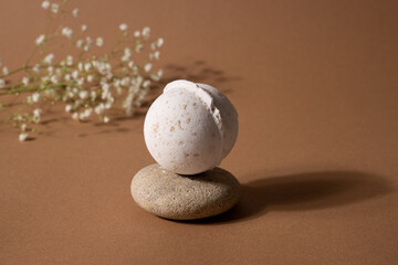 Vanilla aroma bath bomb in spa composition with dry flowers and stone on brown background....