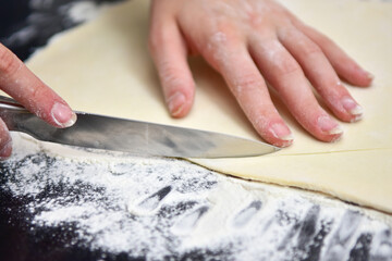 girl cuts the dough with a knife on the croissant baking table at home