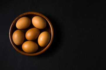 Brown eggs on a plate with black background