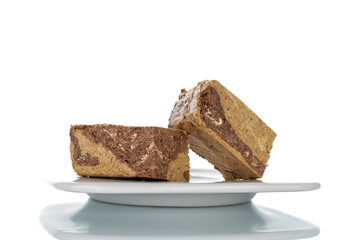 Pieces of sweet halva with chocolate on a white saucer, close-up, isolated on white.