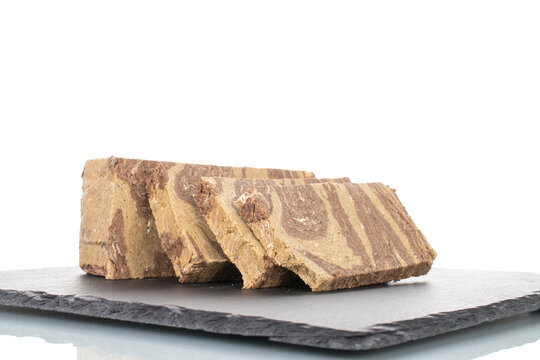 Pieces of sweet halva with chocolate on a slate stone, close-up, isolated on white.
