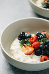 Breakfast bowl of ricotta cheese topped with berries and honey
