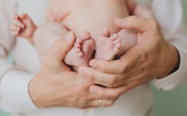 Obraz na płótnie Canvas Father man hands hold tiny feet toes of newborn infant baby