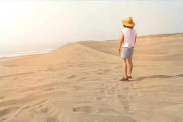 Male young guy wearing hat, staring at ocean and sand dunes in Mexico