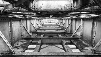 Rusted metal structure of an old railway bridge, covered with moss