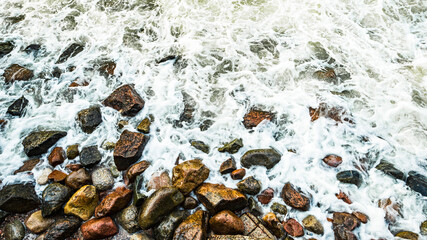 Sea waves slam into the sea rocks on the shore, sea foam on the shore rocks