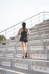 A healthy adult Asian woman running up on concrete stairs of the city stadium to strengthen body