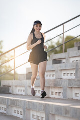 A healthy adult Asian woman running up on concrete stairs of the city stadium to strengthen body