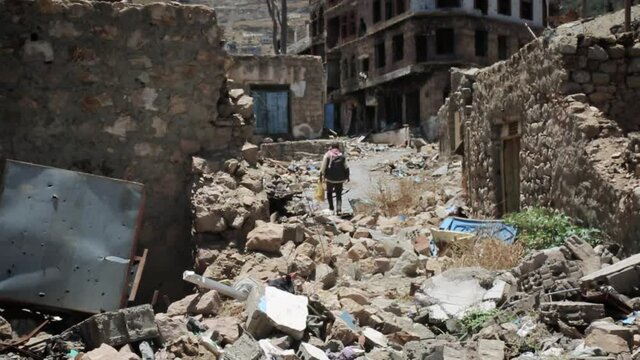 A man walks among the piles of destroyed houses due to the war in Yemen, Taiz