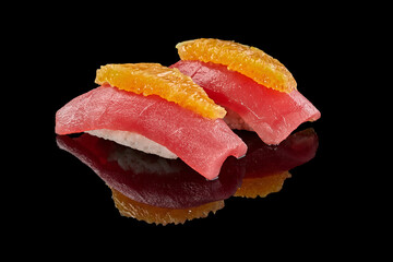 Two nigirizushi with tuna and orange on black background