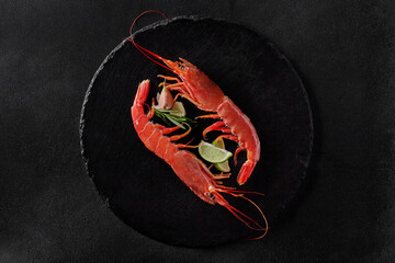 Top view of two shrimps with condiments on round slate board