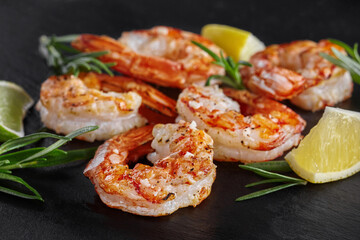 Fried scampi tails with lime, lemon and rosemary on black background
