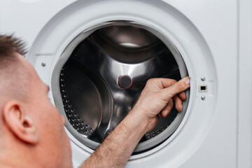 Handyman repairing a washing machine. The hands of man repair a washing machine