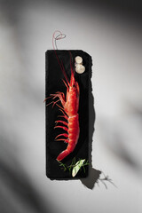 Whole red prawn with condiments on grey background with shadow