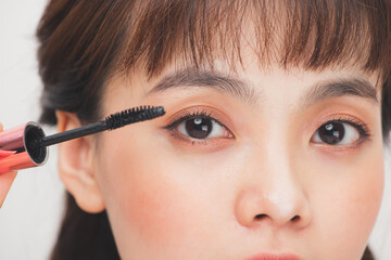 Pretty teen girl woman applying mascara isolated white background.