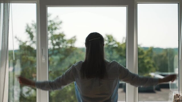 Woman Opening Curtains In Her Apartment.