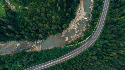 Beautiful aerial view of the road with mountains and forest, road and river, shot from above, carpathians, Ukraine