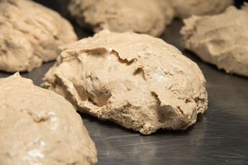 A piece of raw French bun dough against the background of other bun dough pieces. Raw craft bread dough