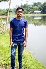 Fototapeta premium A young boy wearing a blue t-shirt to standing and the background behind him is blurry green