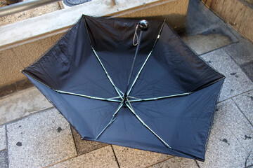 骨の折れた折り畳みの黒い日傘