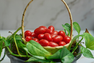 Stack of wet cherry tomatoes in a wooden basket, freshly harvested.