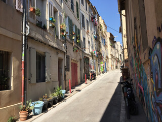 Pastel coloured residential buildings on a calm and friendly street on a summer sunny day in Le Panier - Marseille's oldest and most visited neighborhood.
