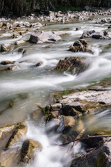Fototapeta na wymiar Smooth water and stones, river and wild nature, mountains, little waterfall